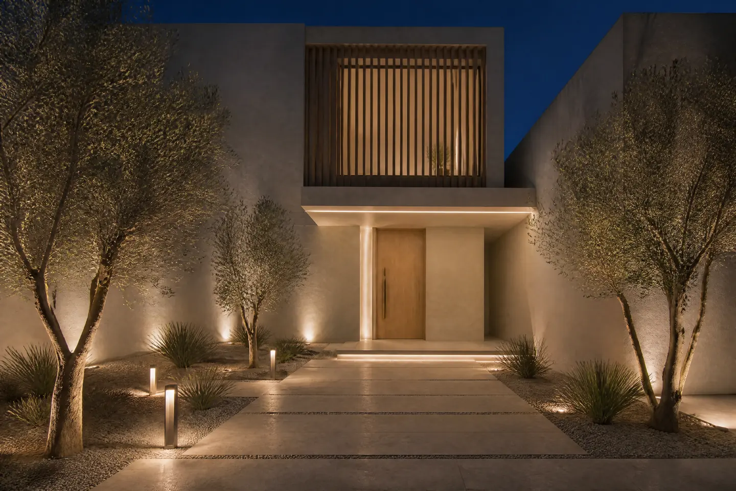 A villa entrance at night with an oak door, a light-line canopy and uplit olive trees