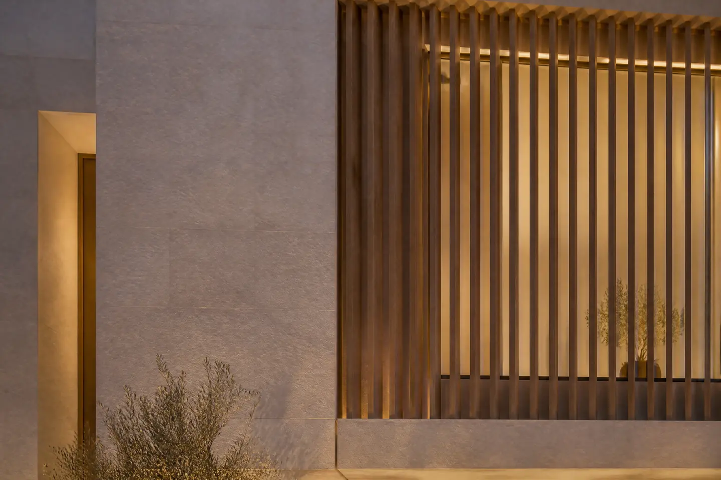 A detail of vertical timber slats on a limestone facade in evening light